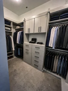 Styled modern gray walk-in closet with hanging clothes and black hardware accents