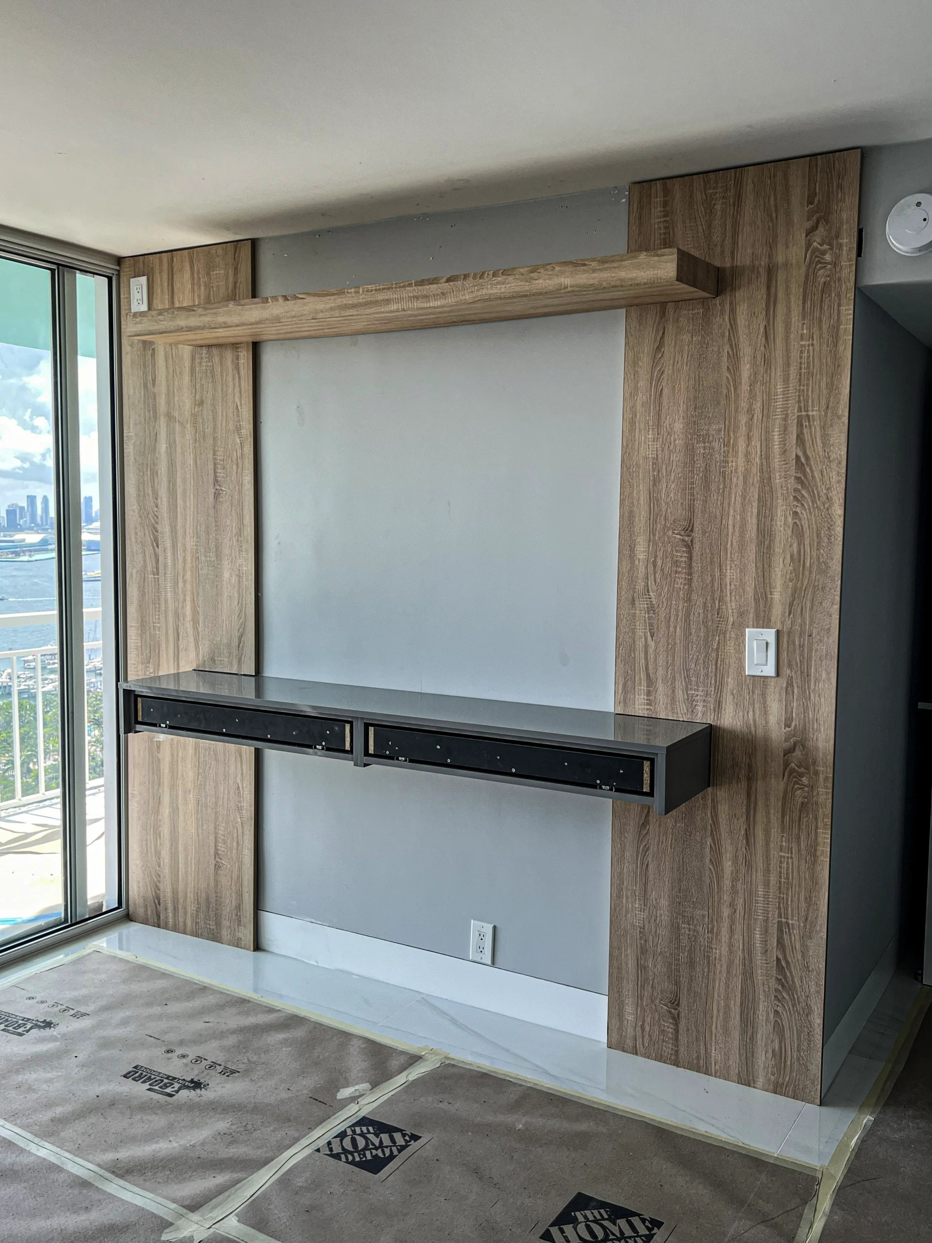 Custom entertainment center featuring a wood panel and marble TV wall with floating console in Fort Lauderdale, FL