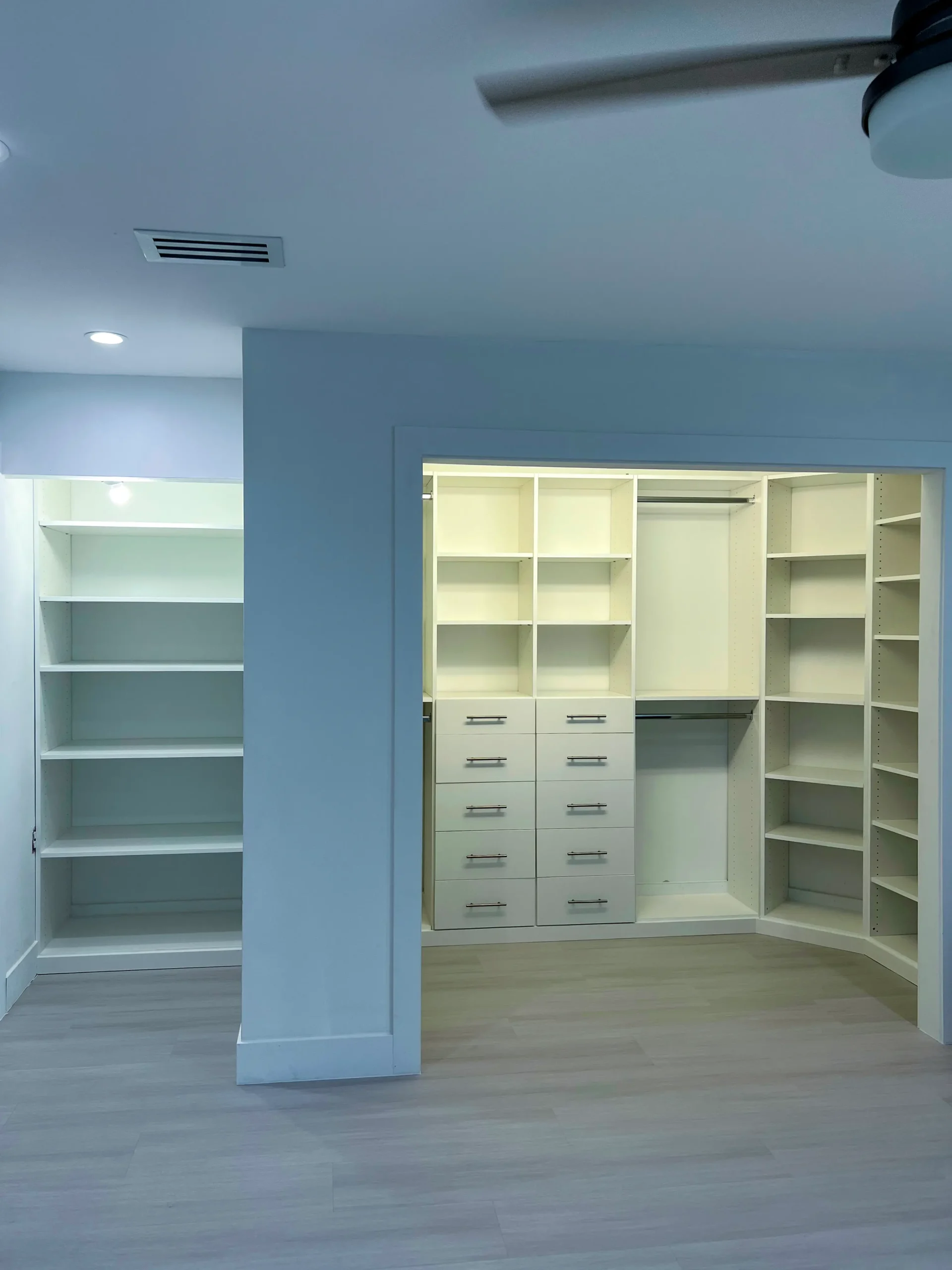 Custom walk-in closet system in white melamine with adjustable shelving, ten drawers and corner radius shelves, custom built and installed in a Parkland, FL bedroom by Custom Closet Florida.